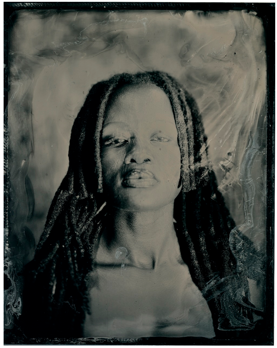 Black-and-white portrait of a person with long braids against a textured backdrop