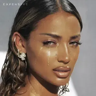 Close-up portrait of a woman with glossy makeup and teardrop makeup on a gray background