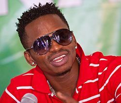 Person in red striped shirt and sunglasses speaking into a microphone at an event