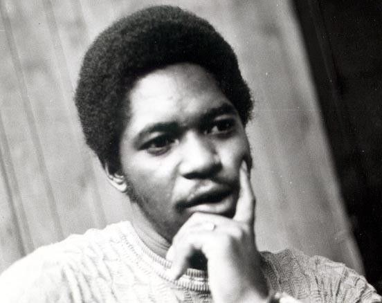 Black-and-white portrait of a person resting their chin on their hand, looking thoughtfully to the side.