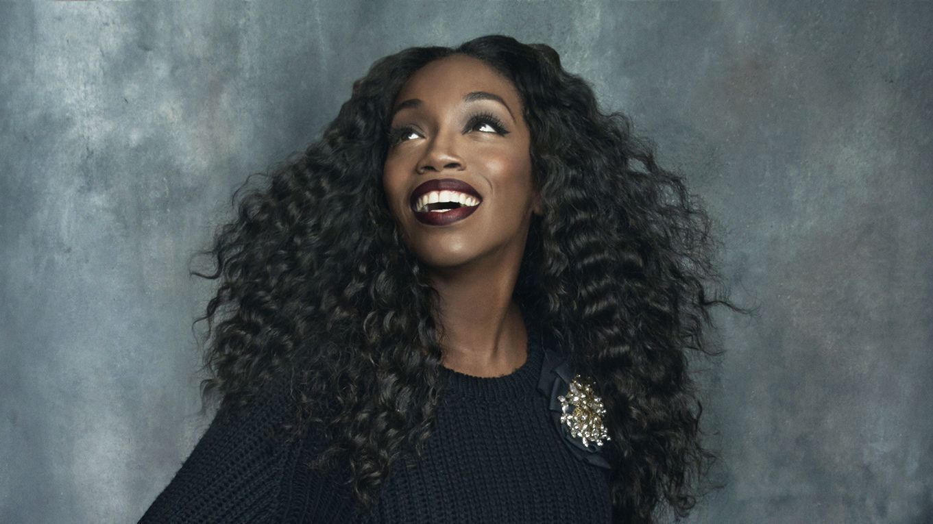 Smiling woman with curly hair looking up against a gray studio backdrop