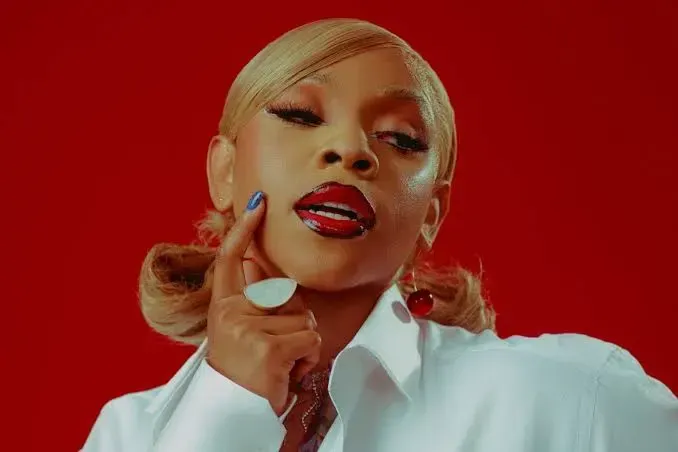 Portrait of a woman with blonde hair and red lipstick against a vivid red background