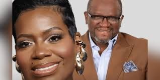 Two smiling people in studio portraits, one close-up in front and one in a tan blazer behind.