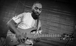 Man playing electric guitar on stage in black-and-white photo