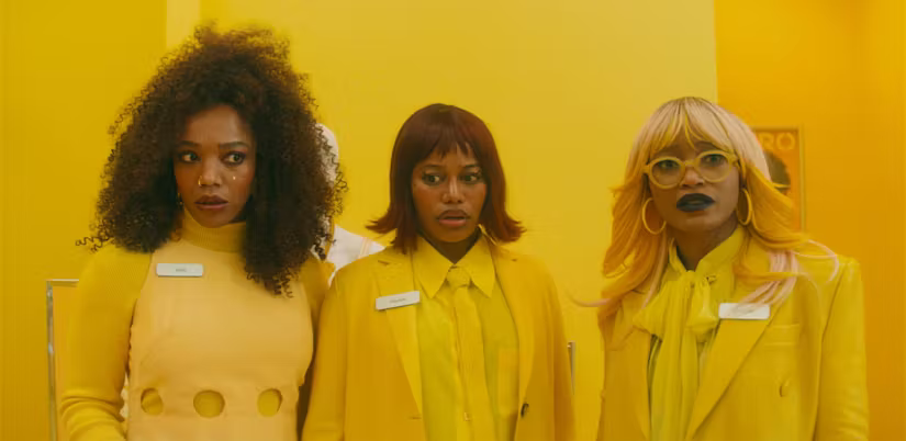 Three people in yellow outfits posing against a yellow background