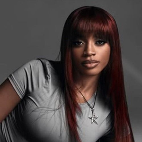 Portrait of a woman with long red hair in a gray shirt against a dark background