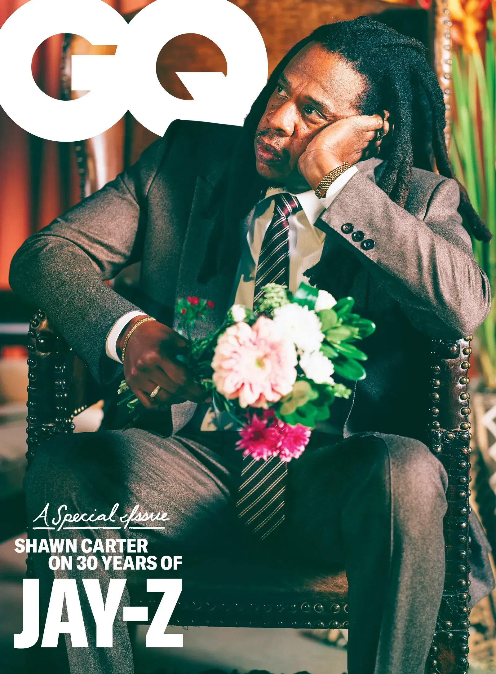 JAY-Z seated in a suit, holding flowers, on a GQ cover with text “10 years of JAY-Z”