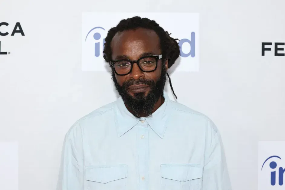 Man in white shirt and glasses at a step-and-repeat event backdrop