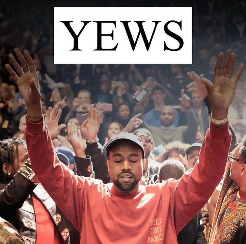 Man in pink shirt raising hands in a cheering crowd, with “YEWS” text above