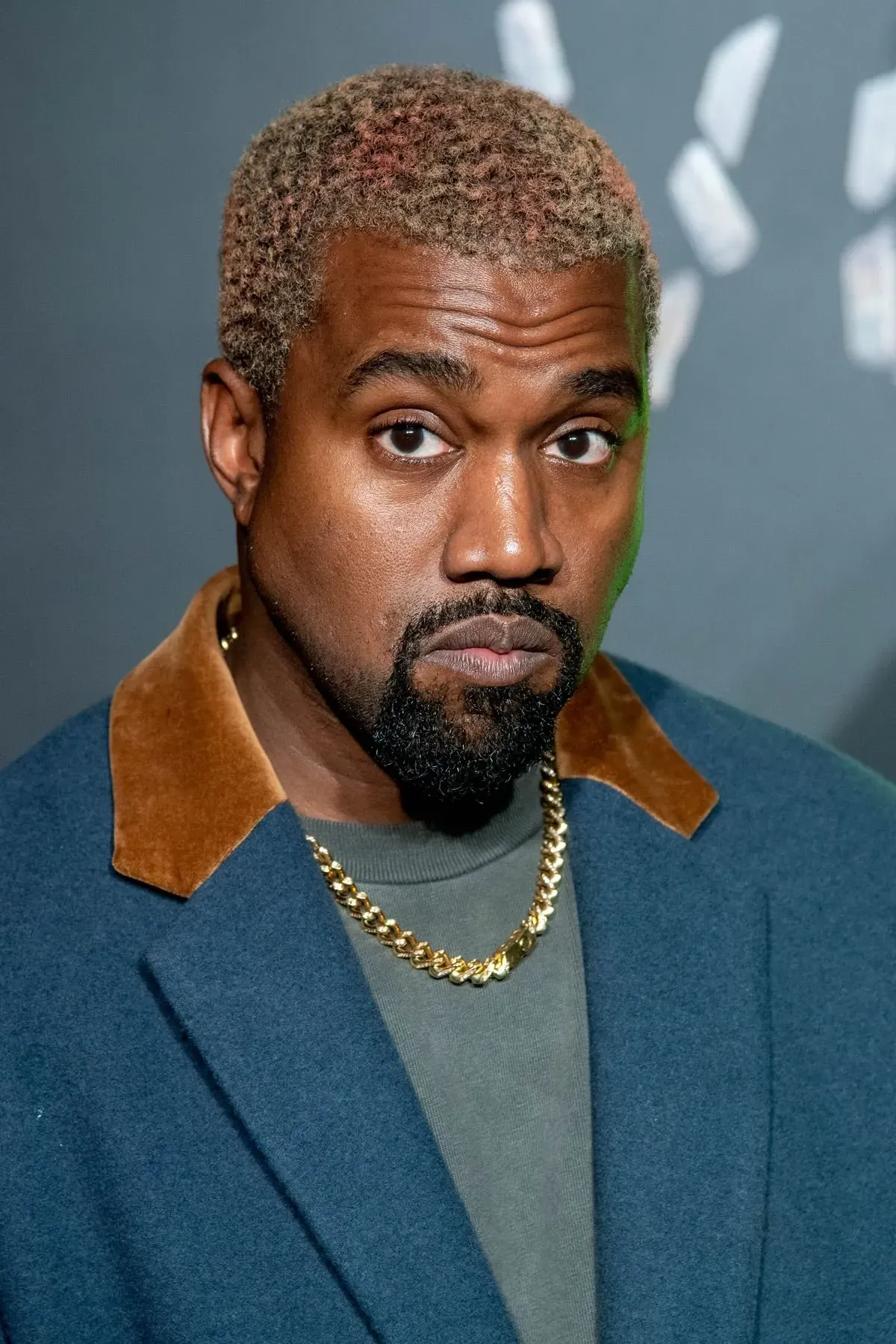 Portrait of a man in a blue coat with a brown collar, gold chain, and neutral expression