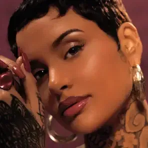Close-up portrait of a person with short dark hair, hoop earrings, and a hand near their face