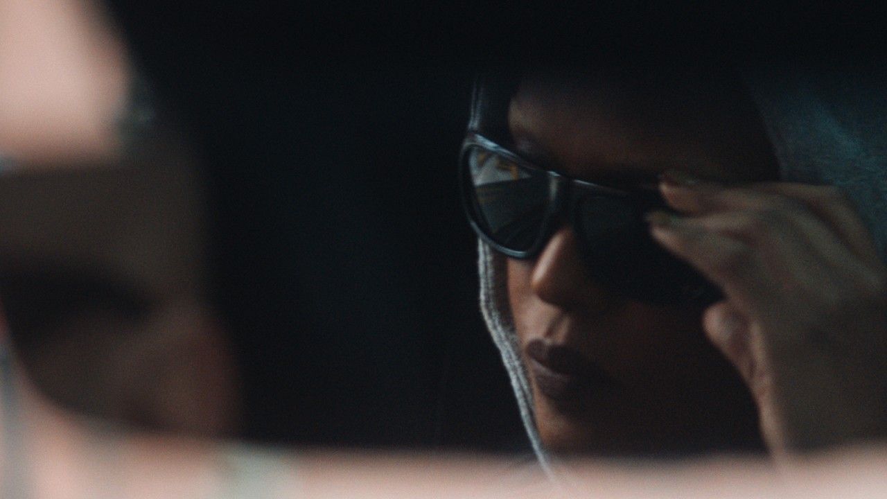 Person adjusting sunglasses in a dimly lit car interior