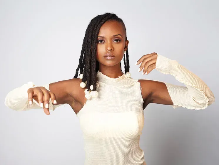 Woman in white sleeveless top posing against a light gray background