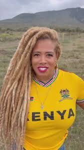 Woman in a yellow Kenya jersey smiling outdoors with mountains in the background