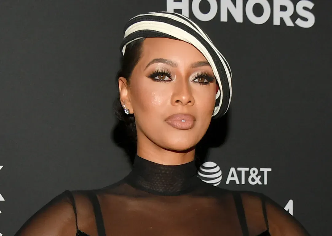 Woman in a black sheer outfit and white hat posing at an AT&T HONORS event.