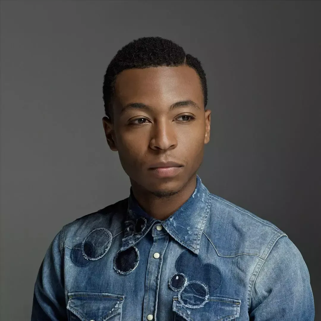 Portrait of a person in a denim shirt against a gray background