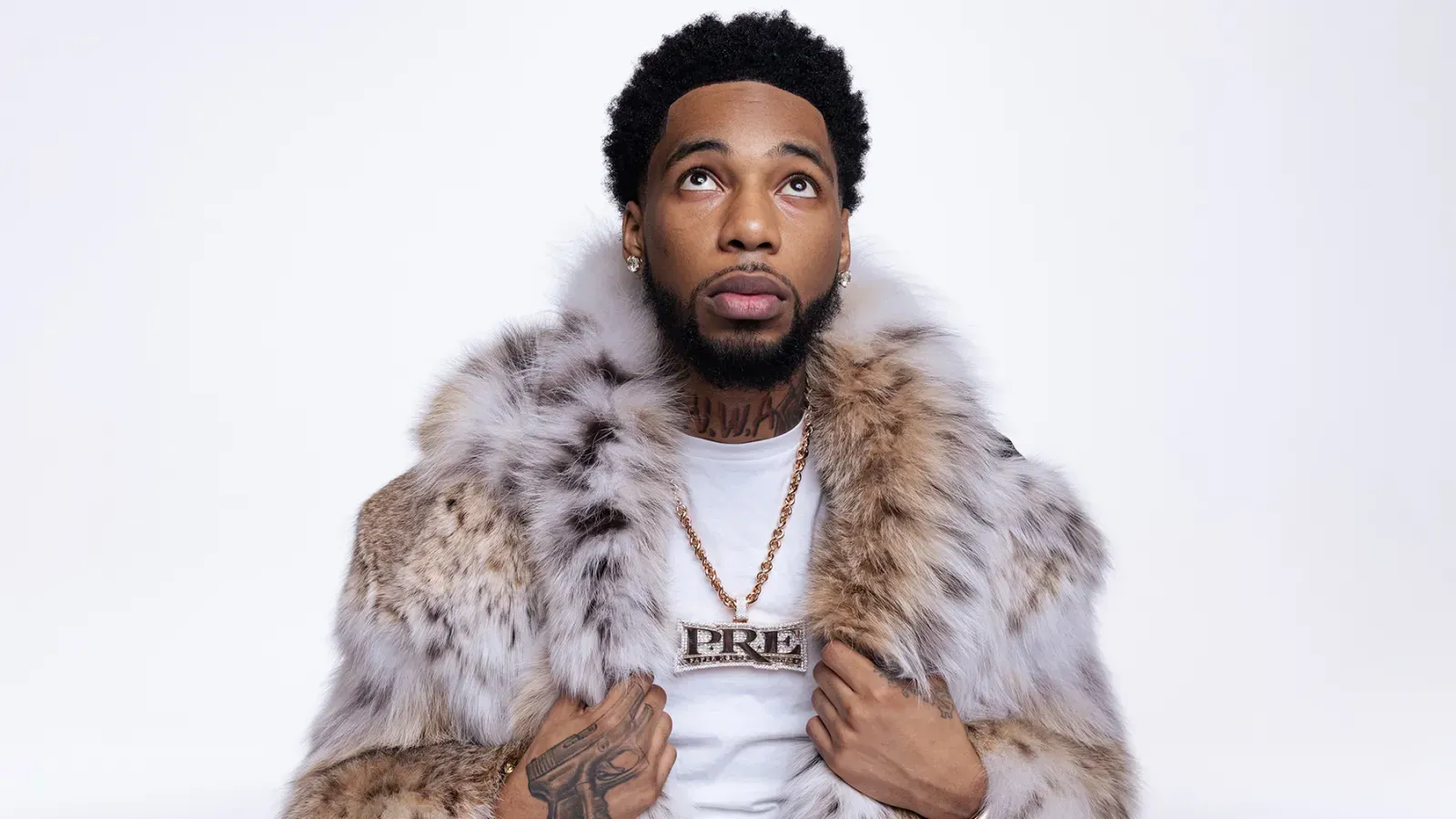 Man in a gray fur coat and white shirt, holding the coat open against a plain white background