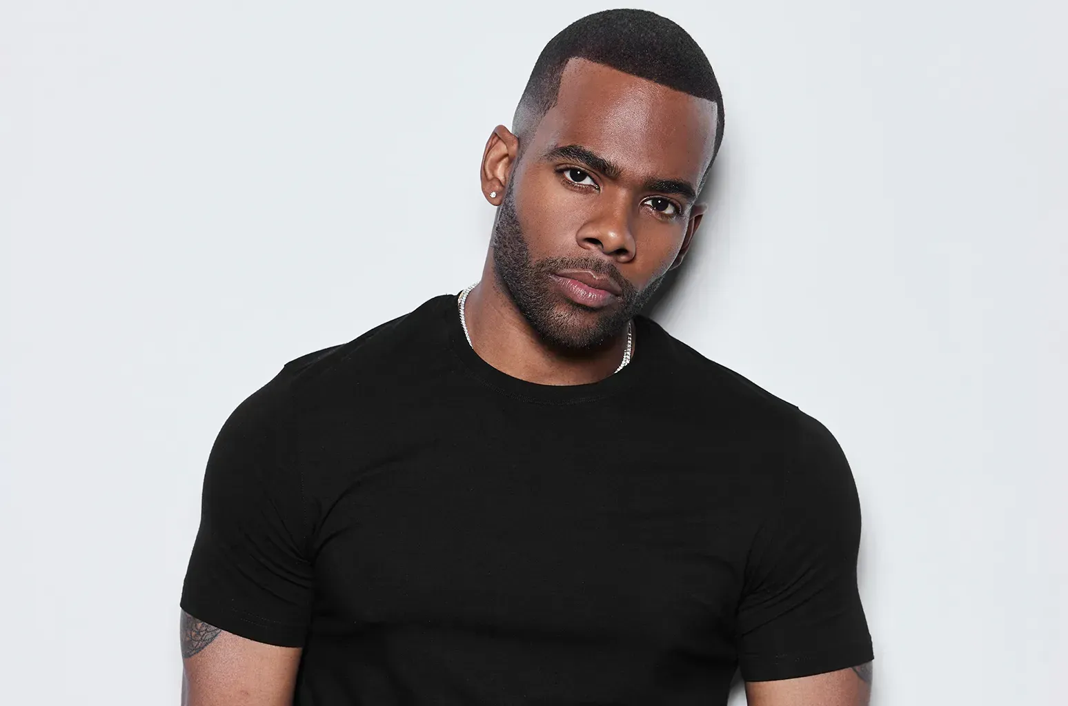 Man in a black T-shirt posing against a light gray background