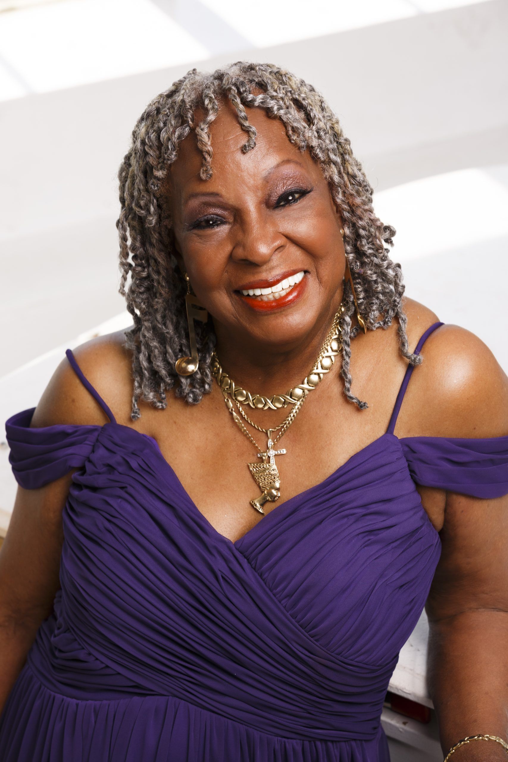 Person draped in glittering fabric against a black background, head tilted upward.