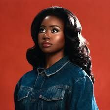 Portrait of a person in a denim jacket against a red background, looking upward with a calm expression