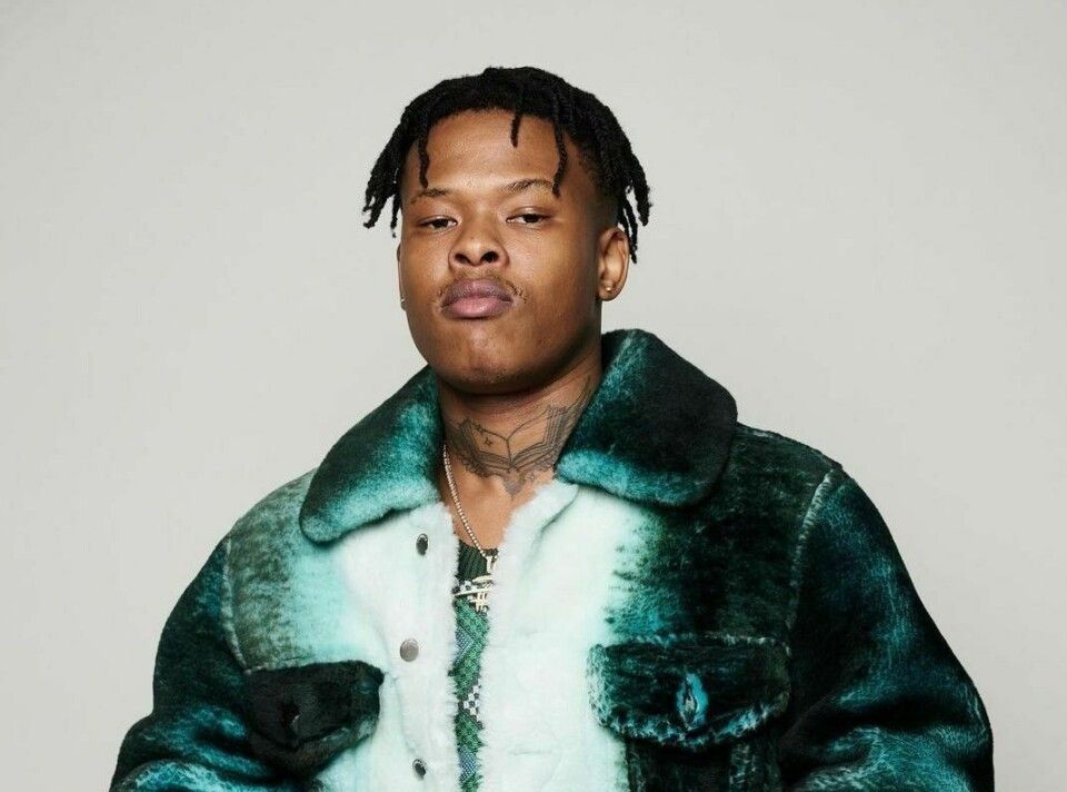 Portrait of a person in a green fur-collared jacket against a plain background