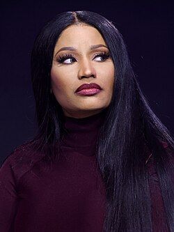 Studio portrait of a person in a burgundy turtleneck, looking to the side against a dark purple background