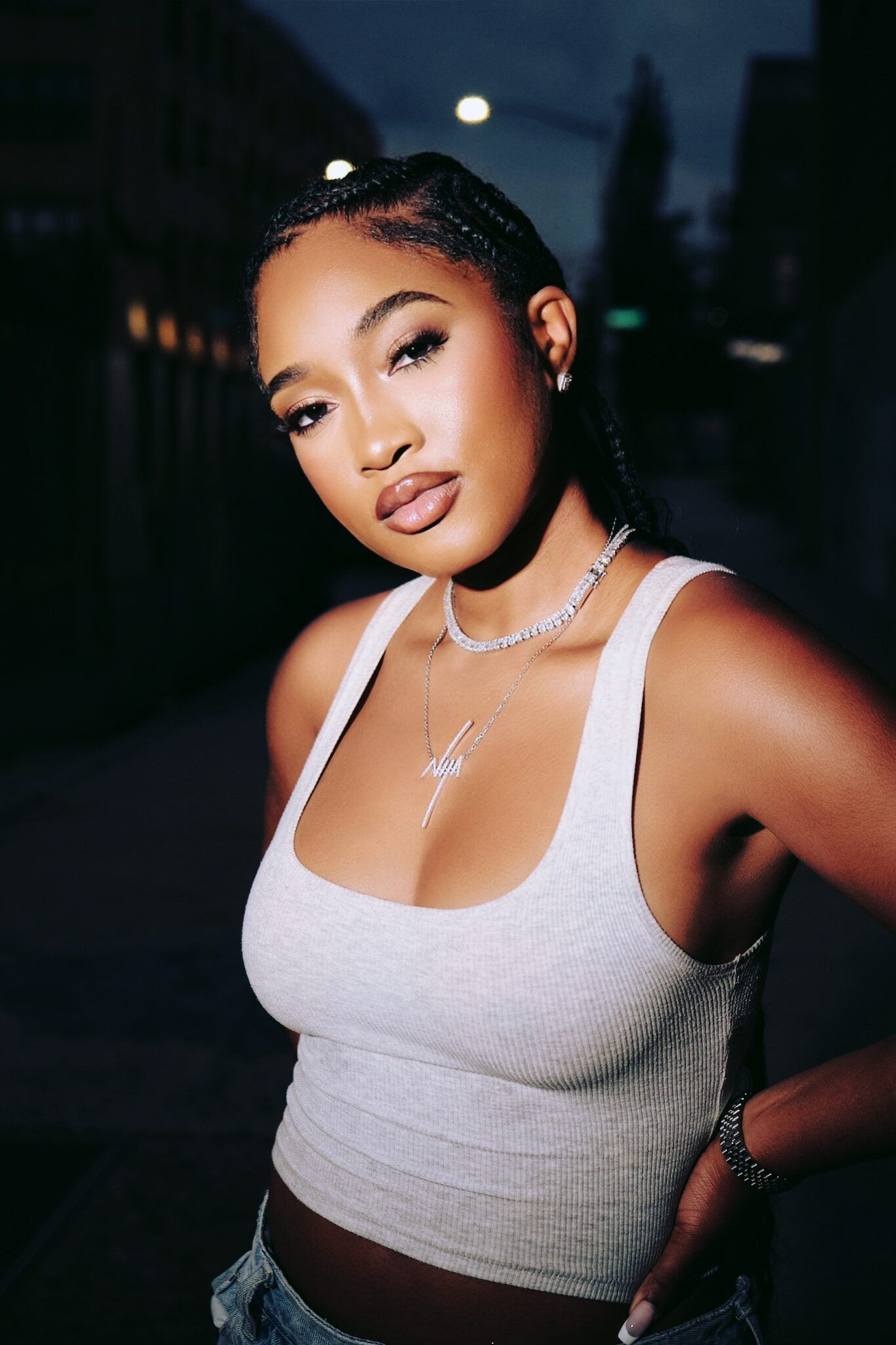 Portrait of a woman in a white halter top, posing outdoors at night with a soft smile