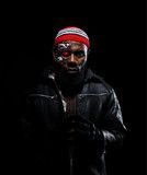 Man in a red beanie and black jacket against a dark background, looking straight ahead.