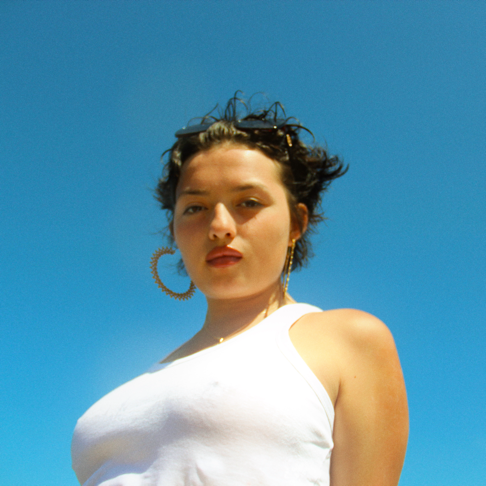 Woman in a white top against a clear blue sky, looking at the camera.