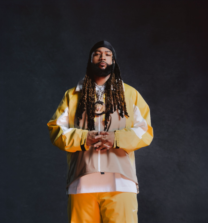 Man in yellow and white outfit standing against a dark studio background