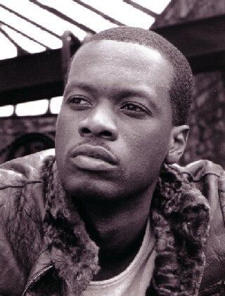 Close-up of a man in a fur-collared jacket, looking off to the side with a serious expression.