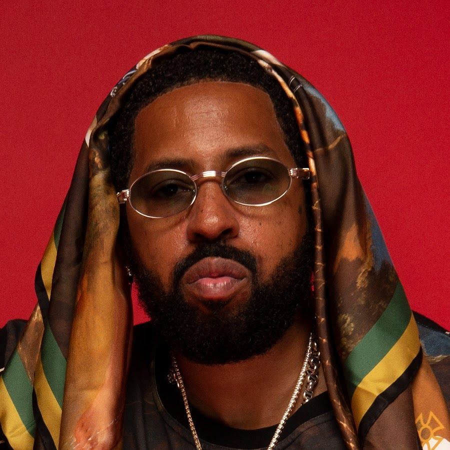 Portrait of a man with glasses and a hooded patterned garment against a red background