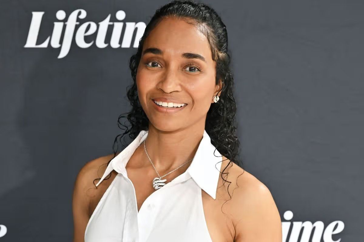Woman smiling in a white sleeveless blouse at a Lifetime event backdrop
