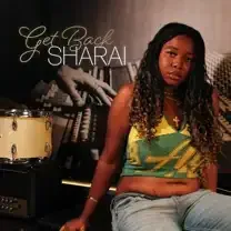 Woman seated by a drum set in a music studio, with “Get Back SHARAI” text in the background.