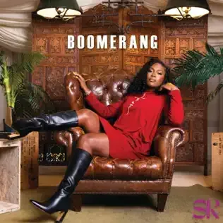 Woman in red dress and black boots reclining in a leather chair under the word “BOOMERANG”