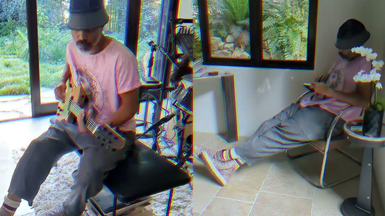 Two men sitting indoors near windows, one playing saxophone and the other looking at a phone.
