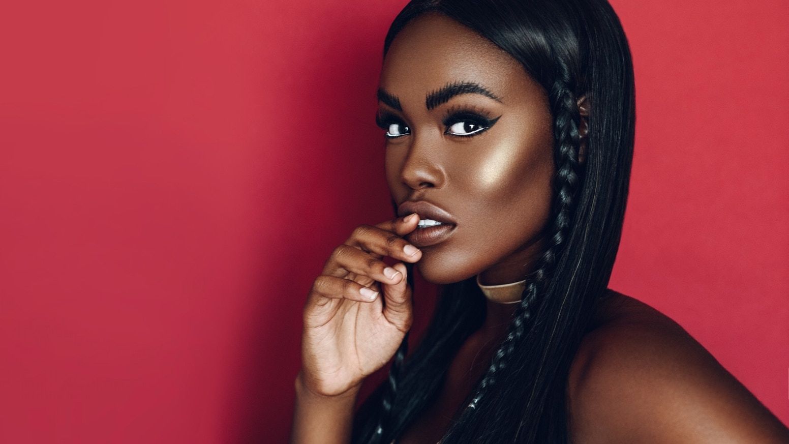 Portrait of a woman with long braids in a black top against a dark studio background