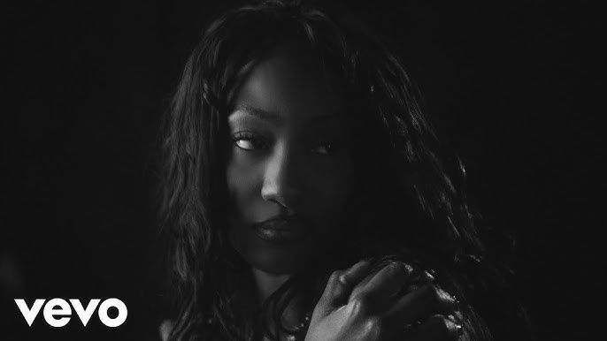 Black-and-white close-up of a woman with wavy hair, face partly in shadow, with a VEVO logo in the corner