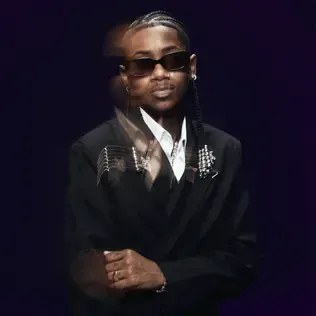 Man in a black suit and sunglasses posing against a dark purple background