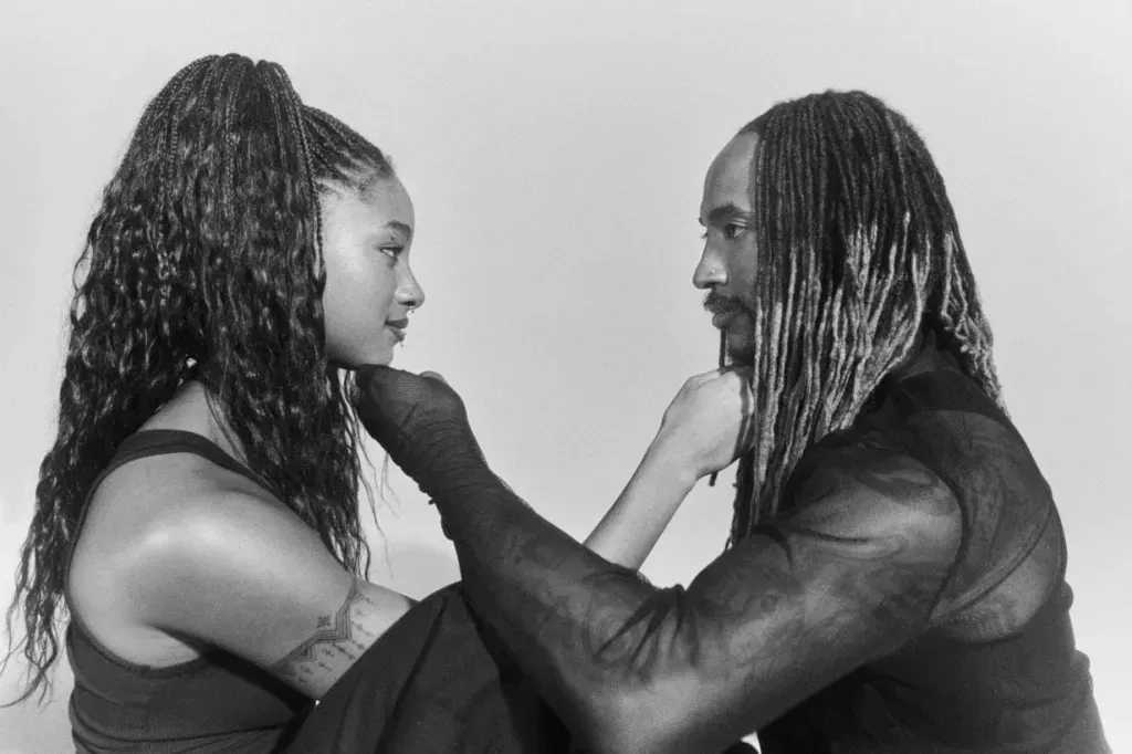 Two people facing each other, gently touching faces in a black-and-white portrait