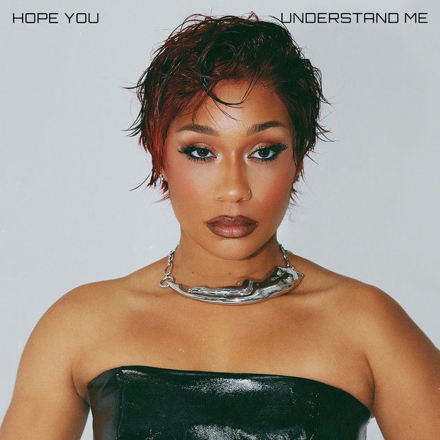 Portrait of a person in a black strapless top and silver necklace against a light gray background with text above