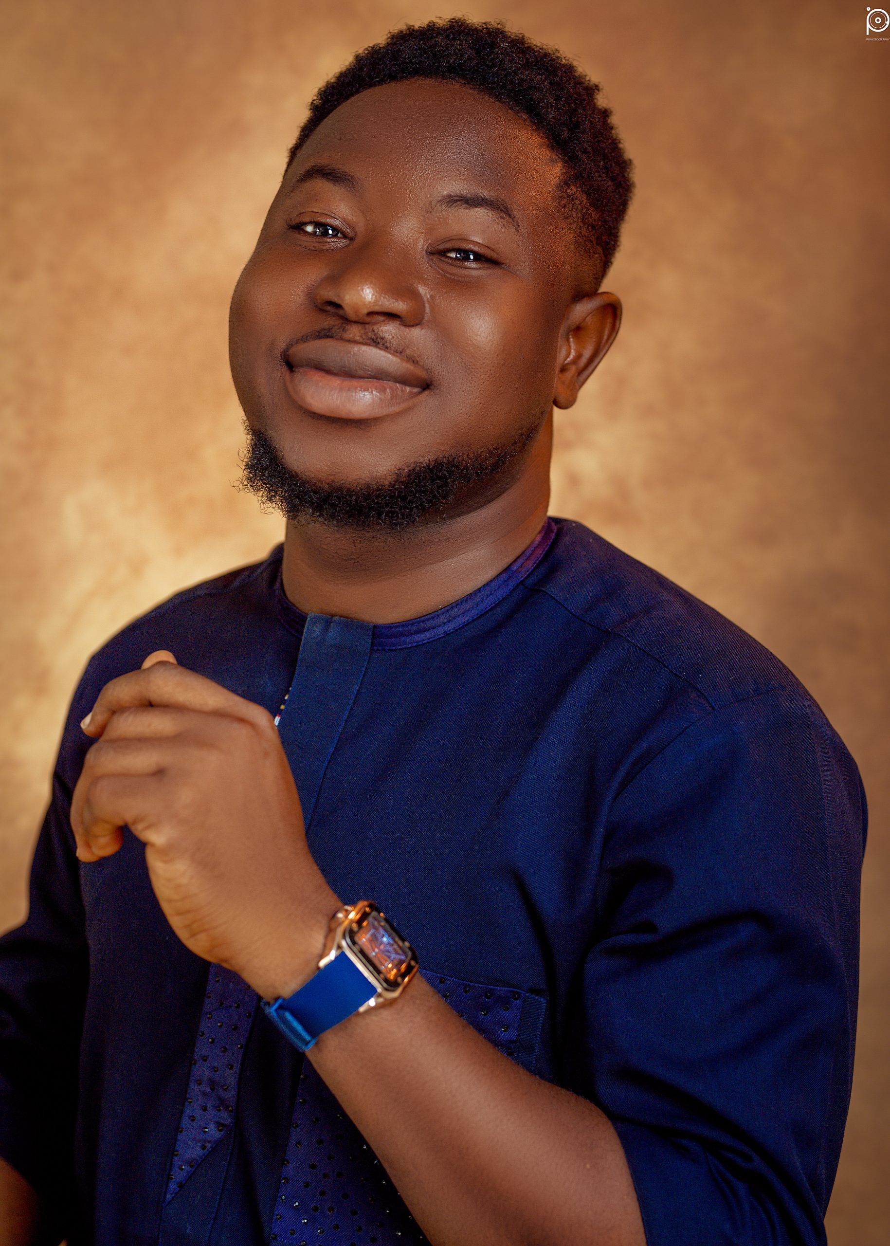 Portrait of a smiling person in a blue shirt against a warm brown background