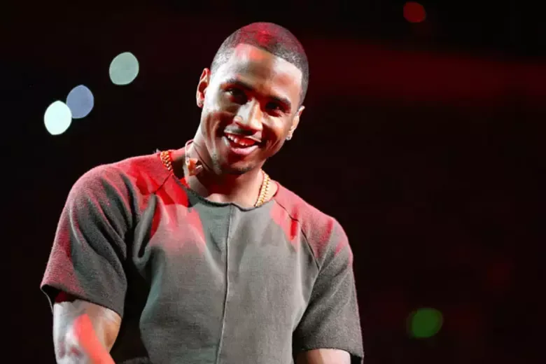 Smiling performer in a gray shirt on a dark stage with red lighting