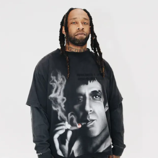 Man wearing a black graphic T-shirt with a large black-and-white portrait, standing against a white background