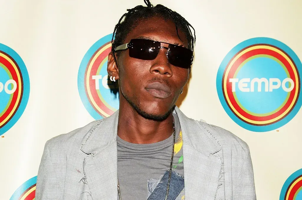 Man wearing sunglasses and a light gray jacket at a Tempo event backdrop