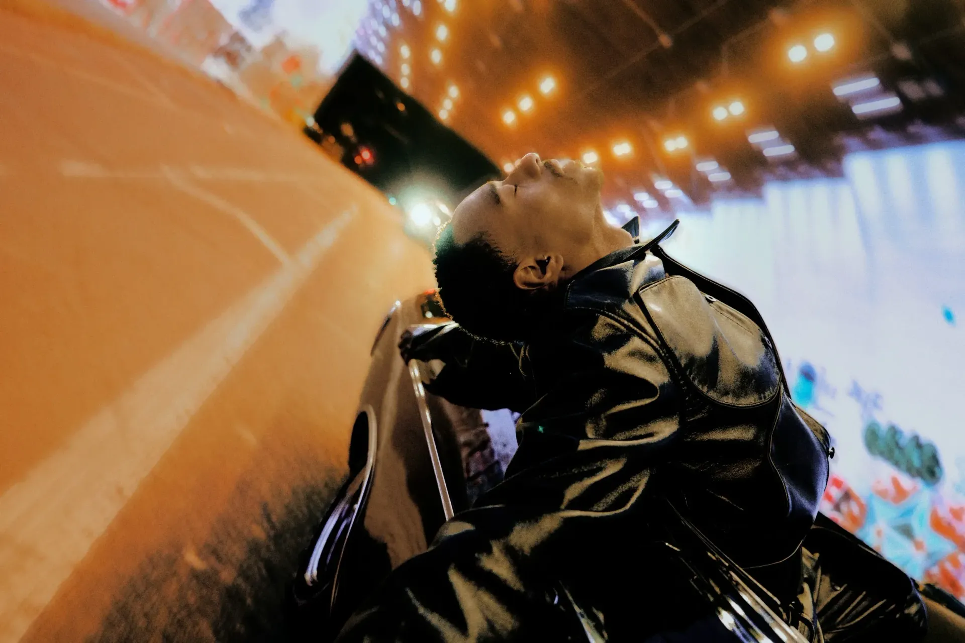 A rider leans into a sharp turn on a motorcycle in a tunnel, with orange lights streaking overhead.