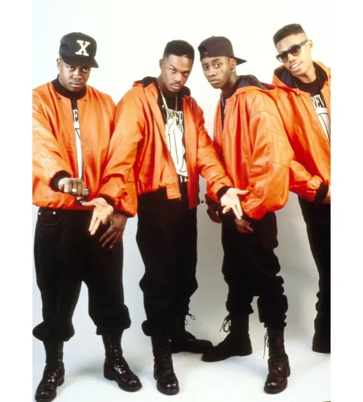 Four people in orange jackets and black pants posing against a white background.