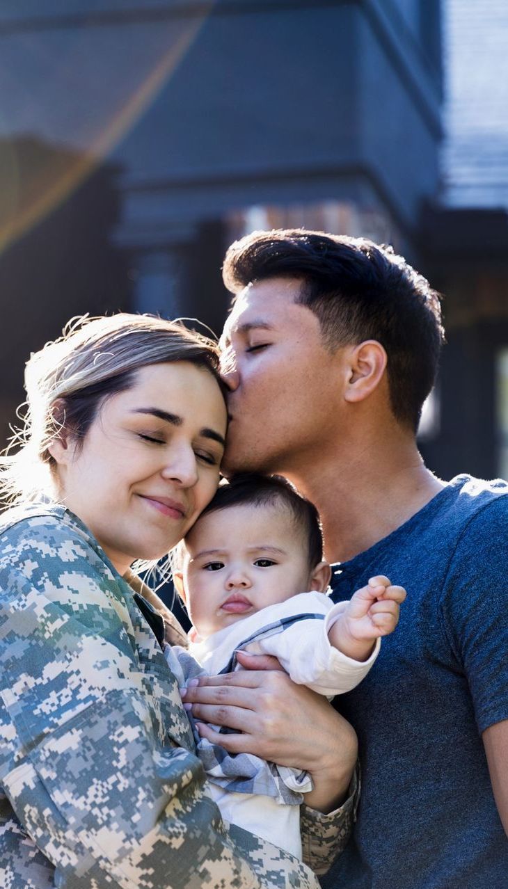 A man is kissing a woman on the cheek while holding a baby.