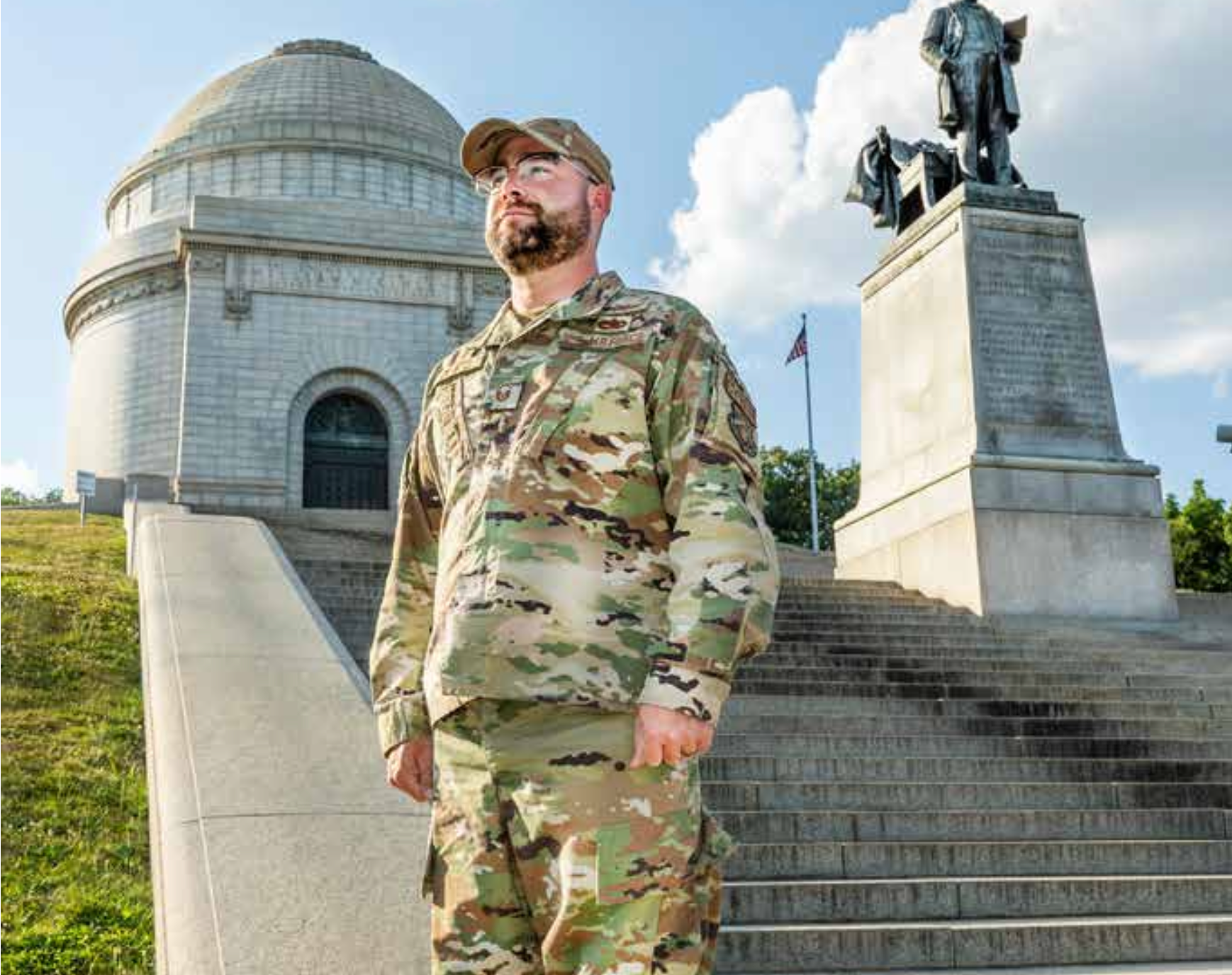 A man in a military uniform is standing in front of a statue.