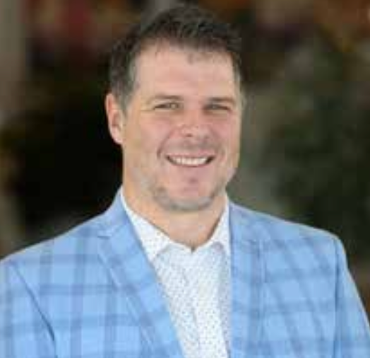 A man in a blue plaid suit and white shirt is smiling for the camera.